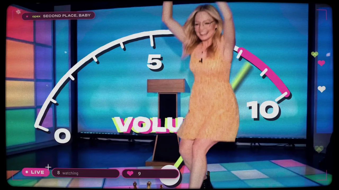A still from the Second Place, Baby music video: a performer dancing on a game-show stage in front of a giant volume dial, with live-stream overlays.